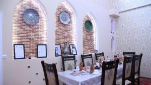 a dining room with a table and chairs with plates on the wall at Khiva Ibrohim Guest House in Khiva