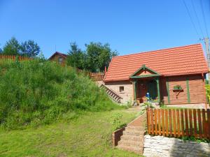 a small house with a red roof on a hill at Dom Letniskowy Ostaszewo in Hartowiec