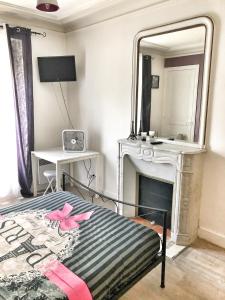 - une chambre avec un lit avec un miroir et une cheminée dans l'établissement Appartement A deux pas de Montmartre, à Paris