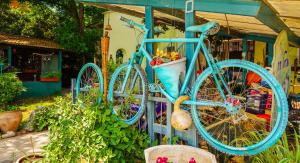 een blauwe fiets is bevestigd aan een hek bij Brush and Wind in Hagoshrim