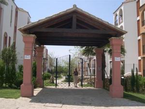 a woman standing under a gate in front at Apartamentos Atlanterra COSTA Y SOL in Zahara de los Atunes