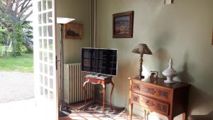 a living room with a television on a dresser and a lamp at La Jouissiere in Soulignac