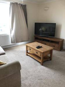 a living room with a television and a wooden coffee table at Henry,s Place in Great Torrington