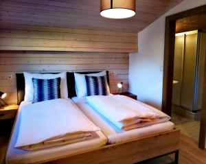 1 dormitorio con 1 cama grande y pared de madera en Haus Vordertiefenbach, en Wagrain