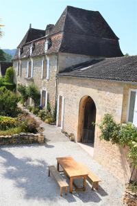 a stone building with a wooden bench in front of it at La Marcillande in Saint-Cyprien