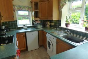 cocina con fregadero y lavadora en Criffel Cottage, en Dumfries