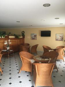 a waiting room with wicker chairs and a table and a tv at Hotel Rias Baixas in Sanxenxo