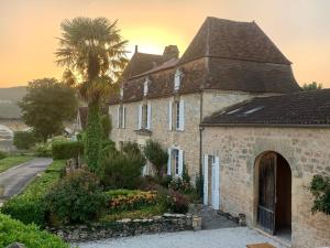 an old brick house with a palm tree in the background at Moon River Grande Maison in Saint-Cyprien