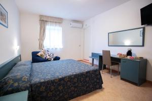 a hotel room with a bed and a desk and a television at Colibrì in Maierà