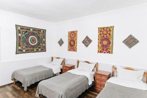 a room with three beds and paintings on the wall at Trip.LE Hostel Samarkand in Samarkand