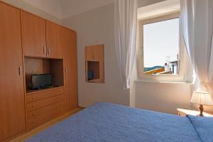 sypialnia z łóżkiem, telewizorem i oknem w obiekcie CASA BICE w mieście Rio nellʼElba
