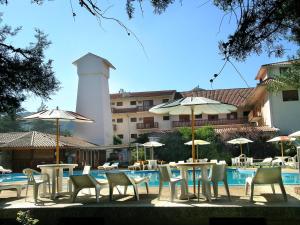 a group of tables and chairs with umbrellas next to a pool at Hotel Edelweiss in Villa General Belgrano