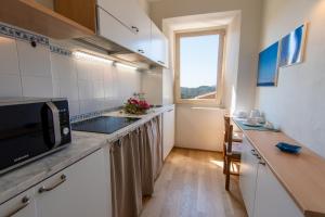 eine kleine Küche mit einer Mikrowelle und einem Fenster in der Unterkunft CASA BICE in Rio nellʼElba