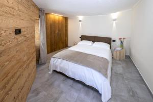 a bedroom with a white bed and a wooden wall at Fenat - Alpine Living in Introd +21 photos
