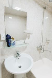 Baño blanco con lavabo y espejo en Trip.LE Hostel Samarkand, en Samarkand