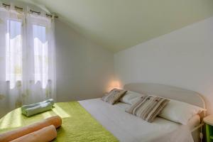 a bedroom with a white bed with a window at Apartment Jasna Near Čikat Bay and Center with Private Parking in Mali Lošinj