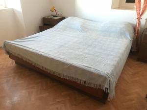 a bed in a bedroom with a wooden floor at Apartman Gracin in Primošten