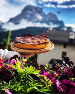 a cake on a cake stand with a mountain in the background at Hotel Oasi in San Vito di Cadore