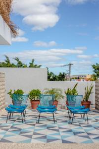 um pátio com cadeiras azuis e vasos de plantas em Studios Downtown Cancun em Cancún