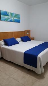 Hotel Rias Baixas في سانكسينكسو: سريرين مع وسائد زرقاء في الغرفة