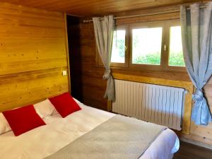 1 dormitorio con 1 cama con 2 almohadas rojas en Residence le Dahu, en Saint-Jean-de-Sixt