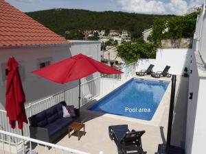 a pool area with a red umbrella and chairs at Villa More in Pučišća
