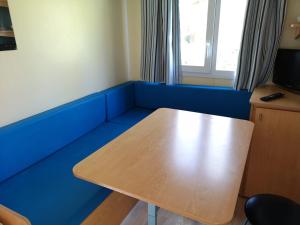 um pequeno quarto com uma mesa de madeira e paredes azuis em Camping Fontfreda em Castellar del Riu