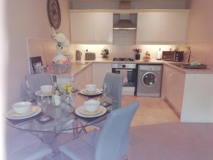 a kitchen with a glass dining table and chairs at 9 Column Mews in Alnwick