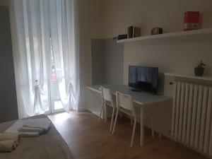Habitación con escritorio, TV y sillas. en Affittacamere La Scala en Lecco