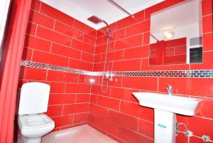 a red tiled bathroom with a toilet and a sink at Appart Clim Wifi 700m de la Plage in Saïdia