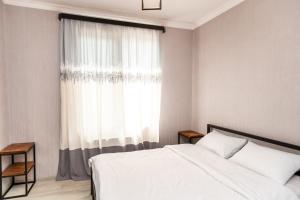 1 dormitorio con cama blanca y ventana en Tamo's Sweet Home, en Tiflis