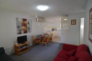 Forest Lodge Apartments في بريزبين: غرفة معيشة مع أريكة حمراء وطاولة
