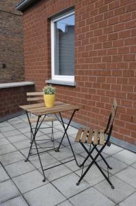 une table et une chaise assises à côté d'un mur de briques dans l'établissement Appartement Jemeppe-Bierset-Liège, à Liège