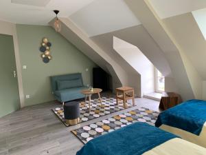 a attic bedroom with two beds and a blue chair at La maison des Légendes in Paimpont