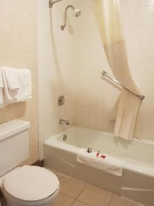 y baño con aseo blanco, bañera y lavamanos. en Travelodge by Wyndham Costa Mesa Newport Beach Hacienda en Costa Mesa