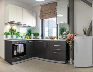 a kitchen with black and white cabinets and a refrigerator at Steel Residence Aparthotel-Free EVCharging & Parking in Timişoara
