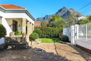 ein Haus mit einem weißen Zaun und Bergen im Hintergrund in der Unterkunft Villa Garda B&B in Kapstadt