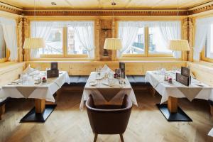 ein Restaurant mit zwei Tischen und weißen Tischdecken in der Unterkunft Hotel Goldener Adler in Ischgl