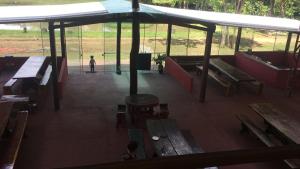 uma criança pequena no meio de um pavilhão com bancos em Estância Cyclo das Águas em Nobres