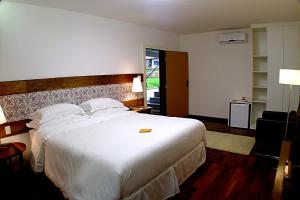 una habitación de hotel con una gran cama blanca y una ventana en Oratório Pousada Boutique, en Tiradentes