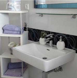 ein weißes Waschbecken im weißen Badezimmer mit Handtüchern in der Unterkunft Apartments Sanja in Hvar