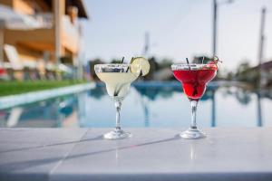 アギオス・ゲオルギオス・パゴンにあるSan Georgio Hotelのプールサイドのテーブルに座ってカクテル3杯