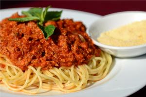 a plate of spaghetti with sauce and a bowl of cheese at Royal Crown Hotel & Spa in Siem Reap