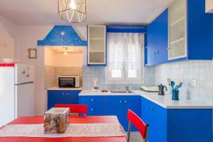 a kitchen with blue cabinets and a table with red chairs at BLUE PARADISE SUITES in Pachaina +11 photos