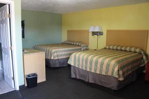 two beds in a hotel room with yellow walls at Deluxe Inn Fort Stockton in Fort Stockton