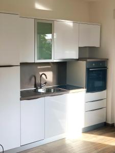 eine Küche mit weißen Schränken und einem Waschbecken in der Unterkunft MILANO in Rogoznica