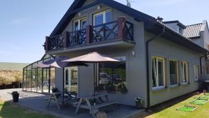 a house with a patio with an umbrella and a table at Pensjonat Morfeusz in Sianozety