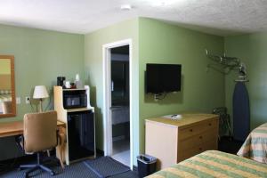 a bedroom with green walls and a desk and a bed at Deluxe Inn Fort Stockton in Fort Stockton