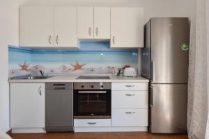 a kitchen with white cabinets and a stainless steel refrigerator at LaMaMa Apartment in Novalja