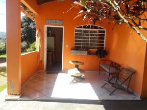 une maison orange avec une chaise et une table dans l'établissement Pousada Veadeiros - Alto Paraiso de Goiás, à Alto Paraíso de Goiás